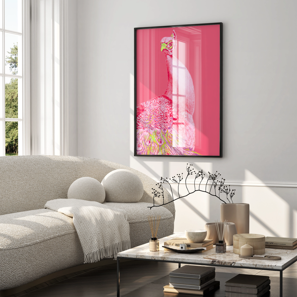 A framed vertical art print featuring a stylized pink peacock illustration hanging on a light gray wall above a beige sofa in a modern living room setting.