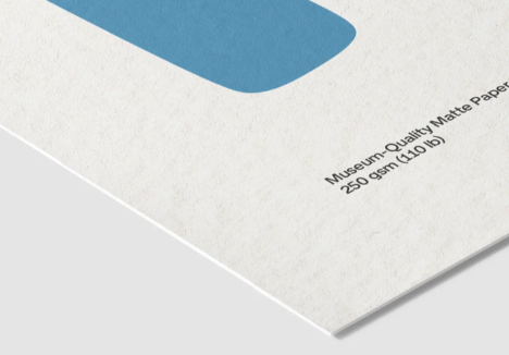 A close-up of a sheet of matte paper with a blue rounded geometric shape and printed text reading 'Museum-Quality Matte Paper' and '250 gsm (110 lb)'.